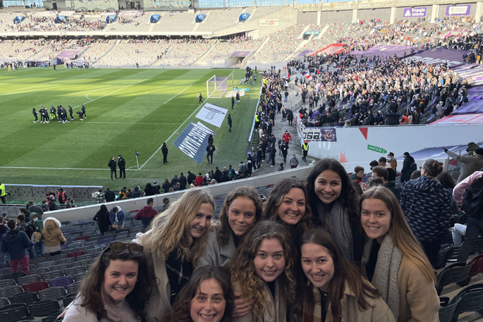 A group of students pose for a picture in a soccer stadium in France