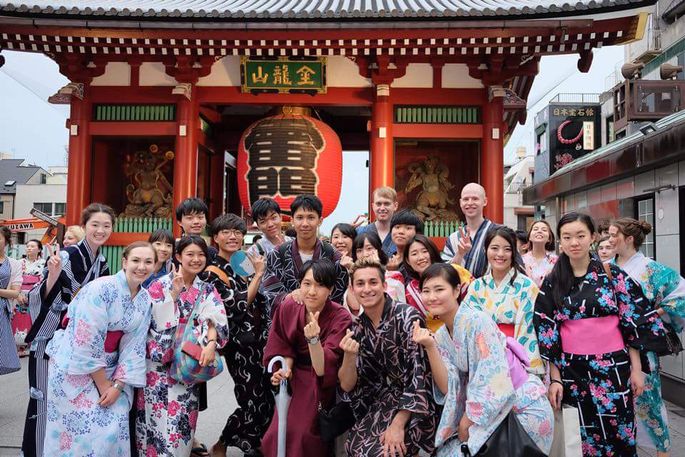 A group of students in traditional Japanese Kimonos pose in front of Japaense architecture
