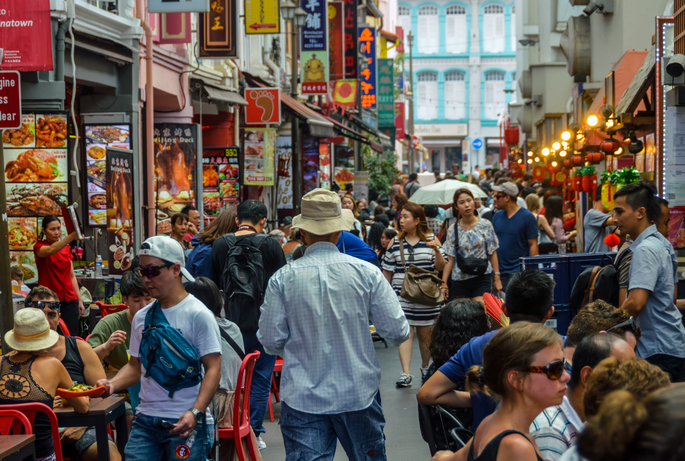 A bustling street scene in Singapore, with signs, food, and people