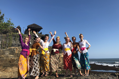 A group of female students pose for a photo on the beach in traditional Indonesian attire