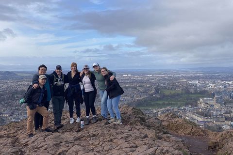 A group of students stand on Arthur's Seat, with the city of Edinburgh sprawling behind