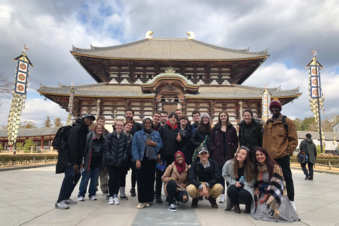 A group of students pose for a photo in front of a Japanese building