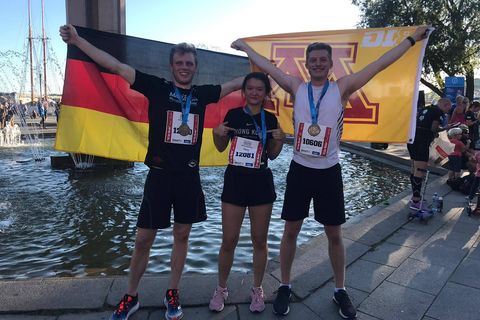 Athletics students holding German & UofM flags