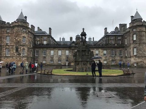 Tourists stand in a rainy courtyard in Scotland