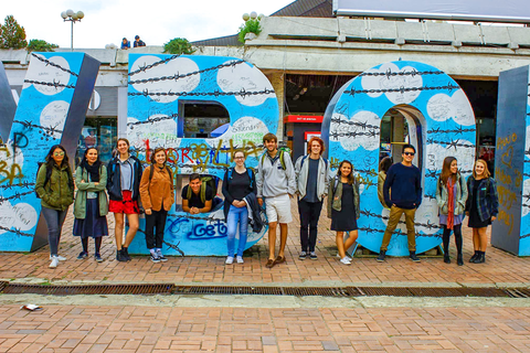 A group of students pose for a photo in front of giant blue letters with white, puffy clouds painted on